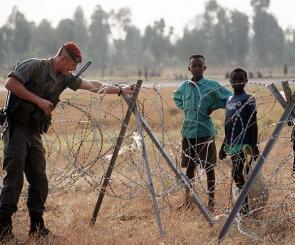 A French soldier, one of the international force supporting the relief effort for Rwandan refugees, adjust the concertina wire surrounding the airport. (Released to Public)