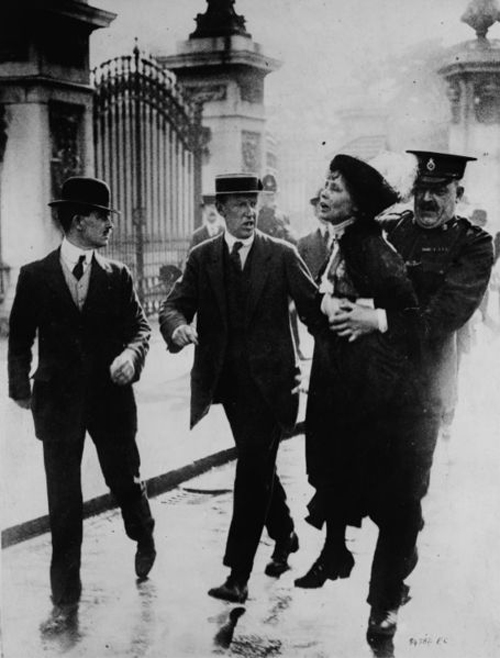 Mrs. Pankhurst being carried by a policeman, as two other men stride along beside, during her arrest