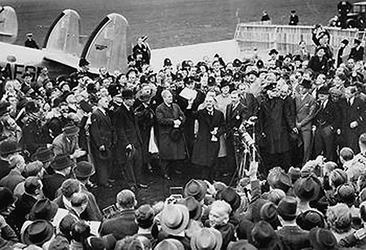 Neville Chamberlain holding the paper containing the resolution to commit to peaceful methods signed by both Hitler and himself on his return from Munich.