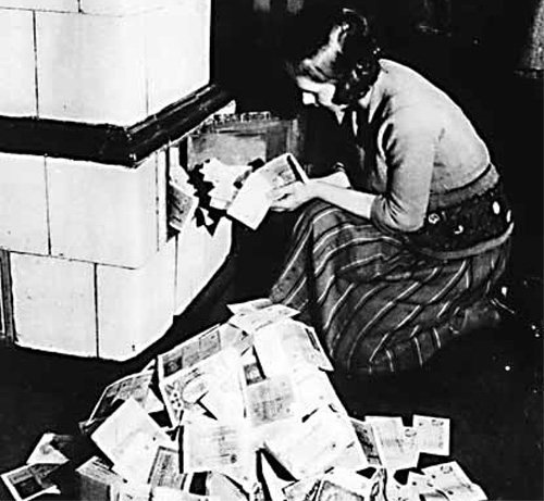 Weimer Germany Inflation 1923–24: a woman feeds her tiled stove with money. At the time, burning money was less expensive than buying firewood.
