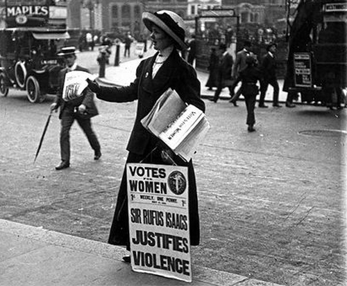 British suffragette with a poster, giving out newspapers.