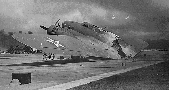 A burned B-17C aircraft rests near Hangar Number Five, Hickam Field, following the attack by Japanese aircraft. Pearl Harbor, Hawaii., 12/07/1941