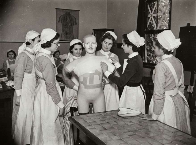 Students receiving from Sister Tutor a lesson in bandaging, for which a life size dummy is used. Atkinson Morley's Convalescent Hospital, October 1940. Source: Historic England Archive MED01/01/1037
