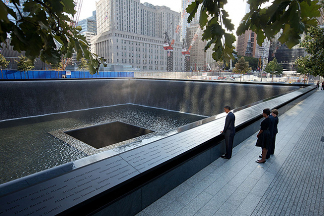 President Barack Obama and First Lady Michelle Obama, along with former President George W. Bush and former First Lady Laura Bush, pause at the North Memorial Pool of the National September 11 Memorial in New York, on the tenth anniversary of the 9/11 attacks, Sunday, Sept. 11, 2011. The North Memorial pool sits in the footprint of the north tower, formerly 1 World Trade Center. (White House photostream / Wikimedia Commons)