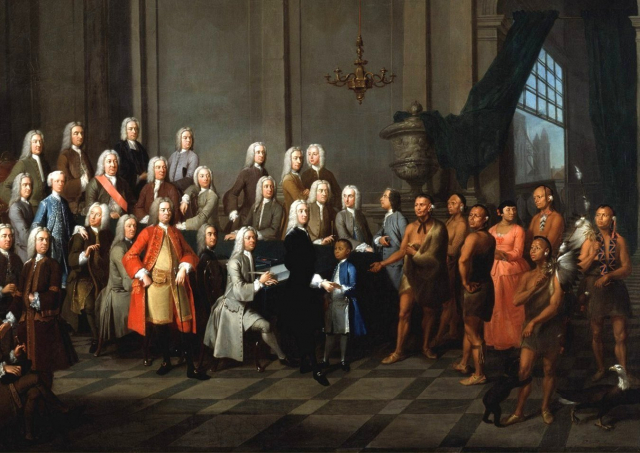 Yamacraw Creek Native Americans meet with the Trustee of the colony of Georgia in England, July 1734. The painting shows a Native American boy (in a blue coat) and woman (in a red dress) in European clothing. Public Domain.